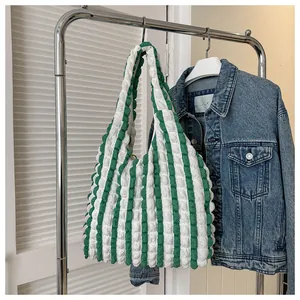 Detail of green and white striped tote bag with bubble texture hanging on a metal rack
