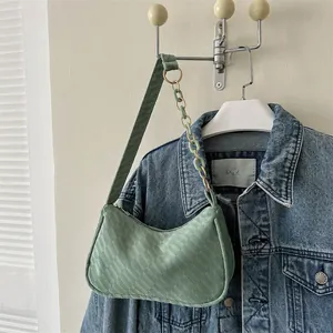 Detail of light green shoulder bag featuring woven texture and decorative link chain