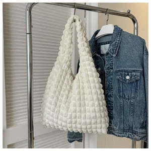 Detail of white bubble texture tote bag hanging on a rack with denim jacket background
