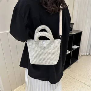 Detalle de bolso bucket crema con textura de burbujas y correa larga ajustable