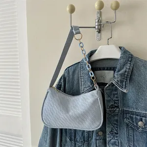 Detail of light blue baguette bag featuring woven texture and resin chain strap detail