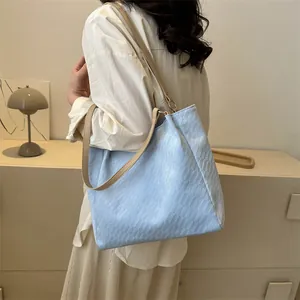 Détail du sac cabas bleu clair avec texture géométrique et fines lanières beiges