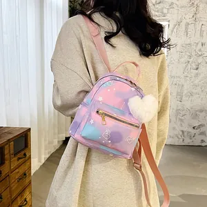 Pastel gradient mini nylon backpack with heart charm shown on model in a cozy indoor setting