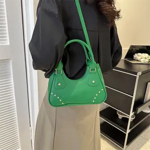 Dettaglio borsa in pelle verde con rivetti a sfera dorati e tracolla regolabile