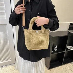 Detalle del bolso tote de ganchillo caqui con textura de punto y botón decorativo blanco