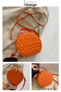 Détails du sac bandoulière orange rond avec texture géométrique et zips dorés en métal