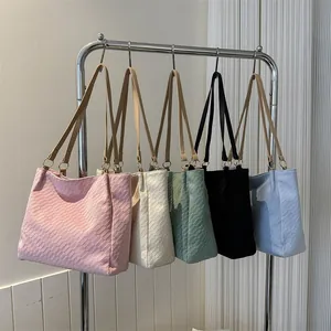 Détail de sacs fourre-tout tissés colorés en rose, beige, vert et bleu avec anses en cuir