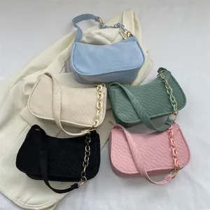 Close-up of quilted corduroy underarm bags in pastel colors with stylish chain straps