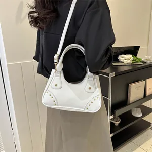 Dettaglio borsa bianca in ecopelle con rivetti dorati e tracolla regolabile per donna