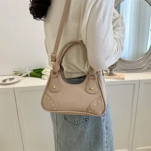 Dettaglio della borsa a mano in pelle kaki con rivetti dorati e tracolla regolabile