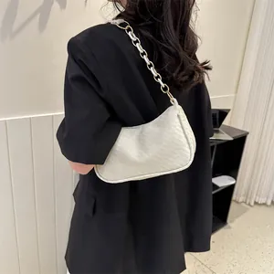 Minimalist white shoulder bag with textured surface and chain strap on a black blazer
