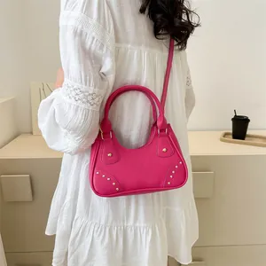 Dettaglio della borsa a tracolla magenta in ecopelle con eleganti borchie dorate