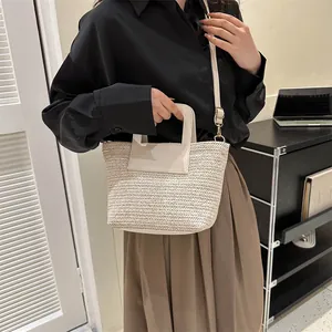 Détail du sac seau tissé crème avec poignées synthétiques et bandoulière réglable