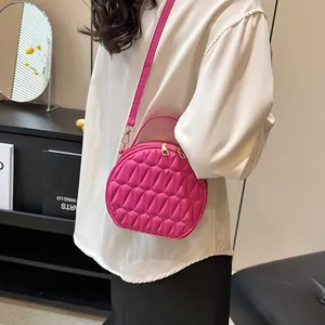 Sac rond magenta avec texture géométrique plissée et détails de fermeture éclair dorés