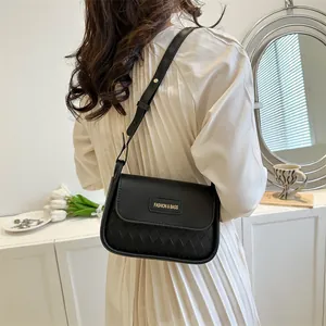 Close-up of black quilted crossbody bag with gold hardware and fashion lettering