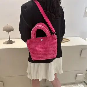 Bolso de pana rosa fucsia con asa y correa al hombro mostrado sobre una modelo