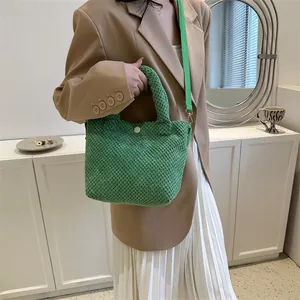 Bolso tipo cubo verde con textura de burbujas, correa larga y detalle de botón blanco