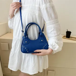 Dettaglio della borsa blu scuro con borchie dorate indossata da una modella
