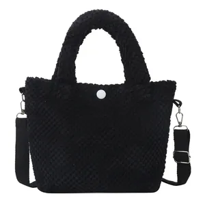 Bolso tipo cubo de lana de cordero negra con botón blanco y correa de hombro ajustable