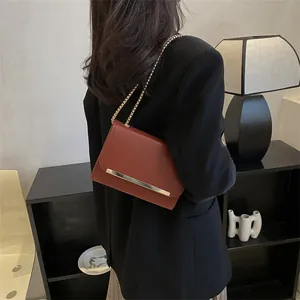 Détail du sac bandoulière en cuir caramel avec chaîne dorée et garniture métallique