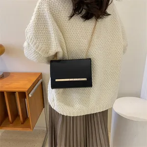 Gros plan du sac à bandoulière noir avec chaîne dorée porté par un mannequin