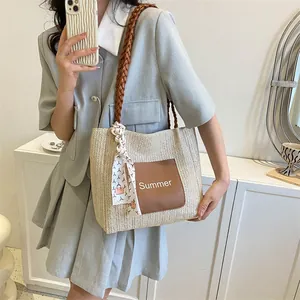 Detail of straw woven tote with leather patch and decorative printed silk scarf handle