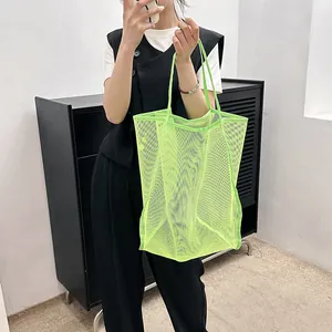 Detalle del bolso de malla verde neón que muestra la textura de la tela y las asas largas