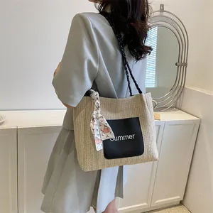 Detail of cream straw tote bag with black summer pocket and decorative silk scarf