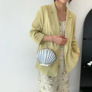 Detail of silver shell-shaped bag with gold chain strap and pearl pendant accent