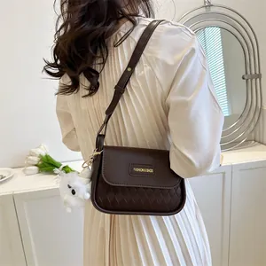 Detailed close-up of a brown quilted small square bag with a plush charm and gold logo tag