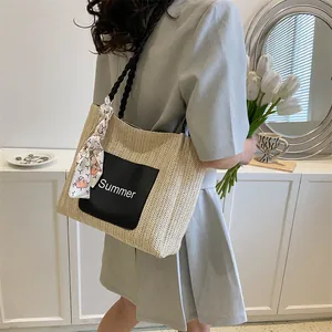 Detail of beige straw tote bag with black 'Summer' patch and geometric silk scarf