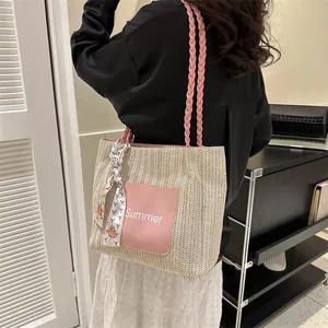 Detail of straw woven tote bag with pink handles and Summer patch on a model