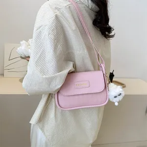 Detail of pink quilted crossbody bag with gold logo plate and white plush charm accessory