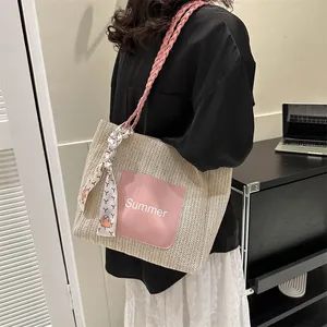 Detail view of woven straw tote bag with pink Summer patch and decorative silk scarf