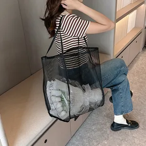 Detalle del bolso tote grande de malla negra con textura transparente y asa ancha