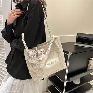 Detail of beige straw tote bag with Summer logo patch and decorative patterned silk scarf