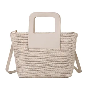 Sac seau minimaliste en paille tressée avec poignées en cuir blanc et une bandoulière
