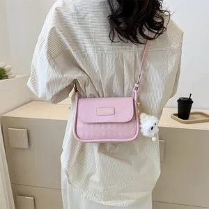 Pink quilted shoulder bag with fluffy keychain worn by a model in casual attire