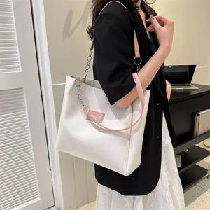 Detail of cream tote bag with pink leather strap and Fashion Instinct text label
