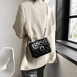 Detail of black quilted crossbody bag with pearl ring buckle and leather chain strap