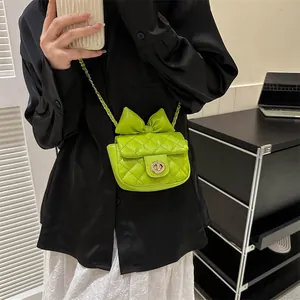 Close-up of bright green quilted crossbody bag with a large bow and chain strap