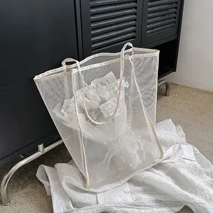 Primer plano del bolso tote de malla blanca mostrando el tejido de red y asas dobles