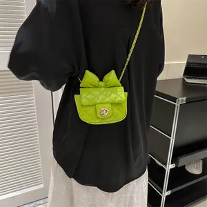 Close-up of bright green quilted mini bag featuring a bow decoration and chain strap