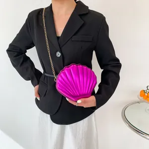 Modern fuchsia shell bag with gold chain strap shown on a stylish model outfit