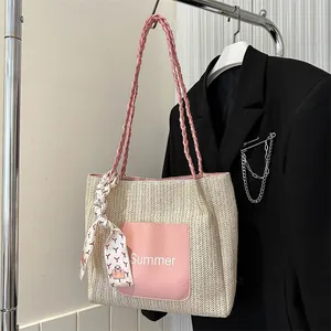 Detail of cream straw tote bag with pink leather pocket and decorative scarf on handle