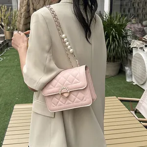 Pink quilted crossbody bag with pearl strap detail shown from a side view on a model