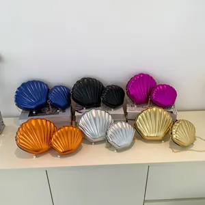Detail of shell-shaped crossbody bags with metallic texture, pearl clasp and chain straps