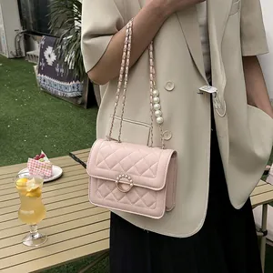 Detail of pink quilted crossbody bag with pearl chain and circular pearl ring buckle