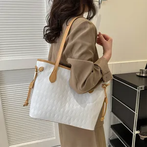 Détail du grand sac cabas matelassé blanc avec garniture en cuir marron porté par un mannequin