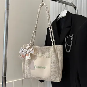 Detail of cream straw tote bag with Summer patch and silk scarf on a display rack